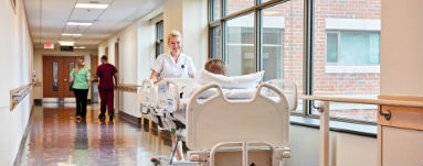 Hospital hallway Hospital patient being transported on a bed down a hallway.