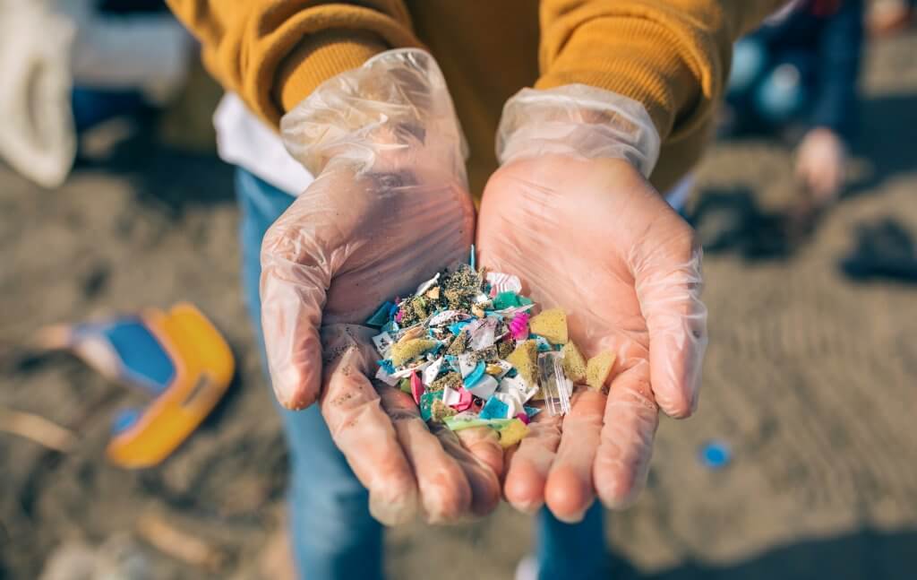 Hands with microplastics on the beach