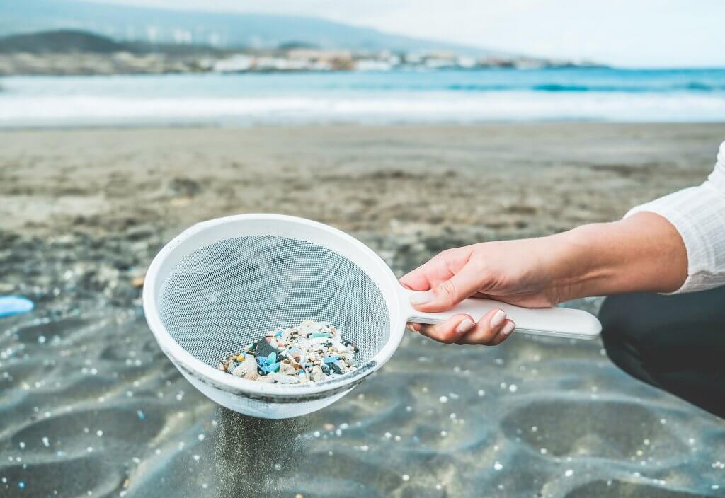 Young woman cleaning microplastics from sand on the beach